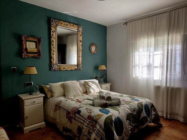Dormitorio doble con pared verde y espejo dorado